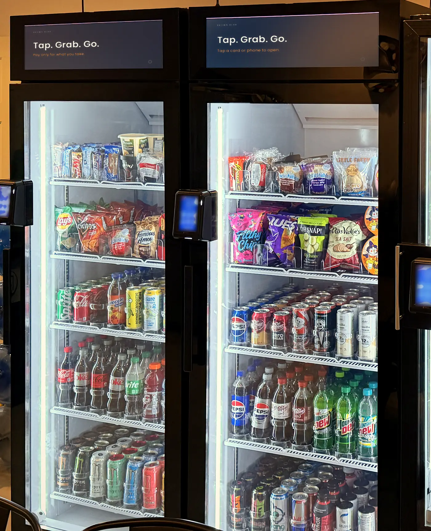 Brown Bear glass-door smart coolers, lit and stocked, each with a tap-to-pay reader on the door.