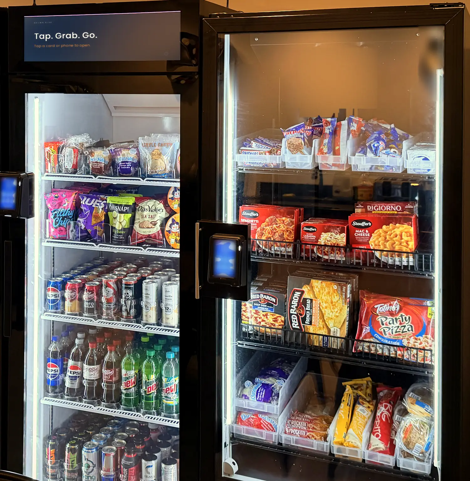 Brown Bear glass-door smart coolers in a break room, lit and stocked, with tap-to-pay readers on the doors.