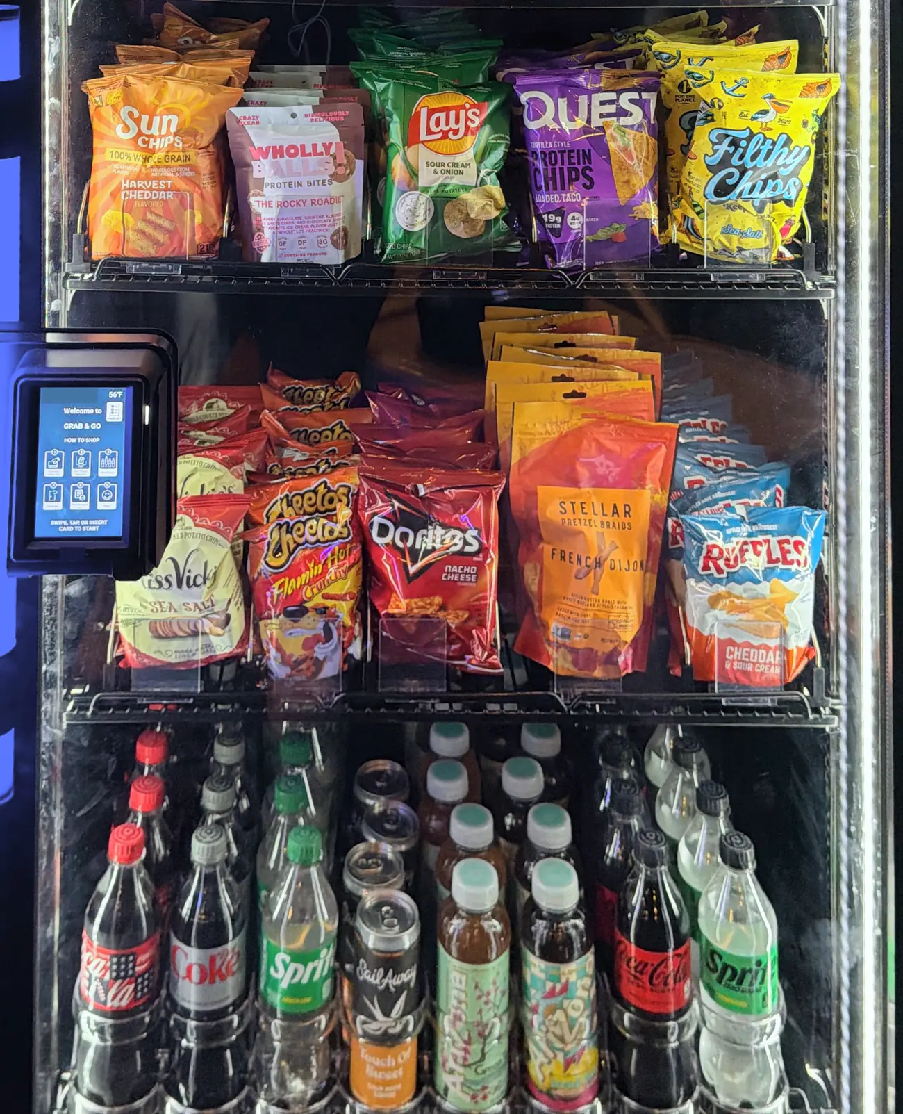 A Brown Bear smart cooler stocked with protein chips, snacks and cold drinks, with a tap-to-pay reader on the door.